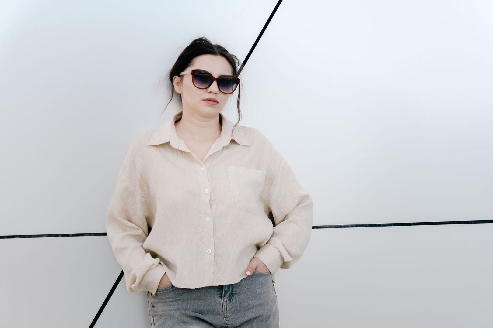 Kvinna i beige skjorta och grå jeans, stylad i dämpade neutrala toner